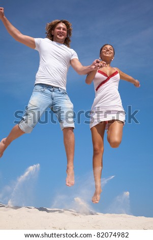 Photo of happy couple in jump with bright blue sky at background