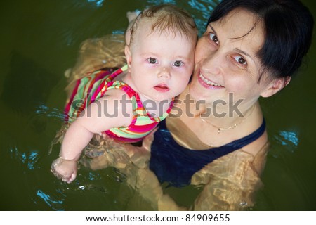 Six month  baby girl at his first swimming lesson wiht mother