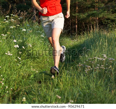Human legs running in the green field