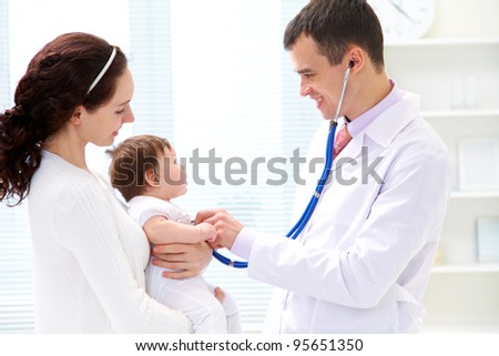 Mother holding baby for pediatrician to examine