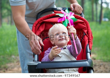 Portrait of little boy in pram playing with toy in father background