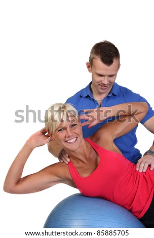 Attractive blonde woman doing side crunches under the guidance of her personal trainer