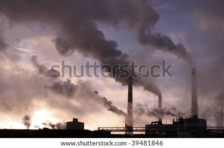 Factory plant silhouette, pipes smoking against dark sky