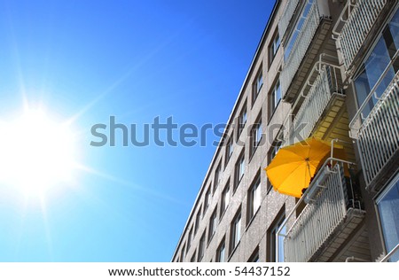 Yellow sun umbrella on balcony in hot summer day burning