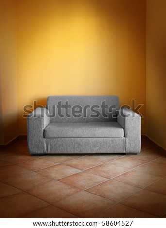 Gray sofa on terracotta tiled floor, in yellow wall room
