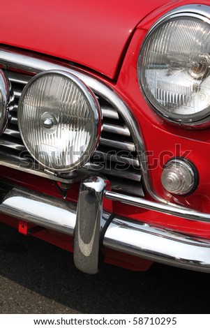 stock photo Chromed grille bumper and twin headlamps of classic red 