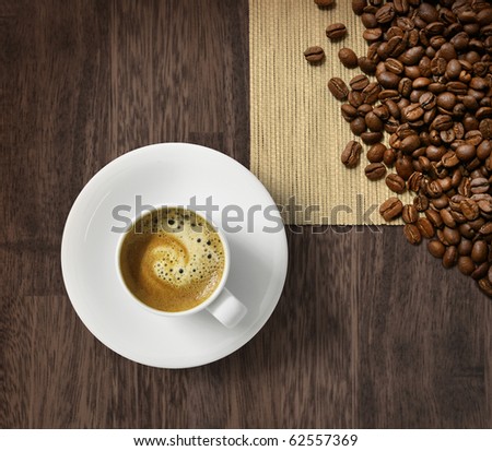 Cup of fresh espresso and roasted coffee beans on dark wooden background