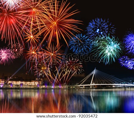 Colorful fireworks reflect from water,  beautiful bridge scenery