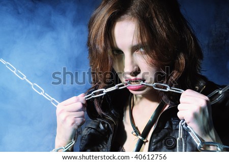 Young girl in leather jacket with chain in hands on blue background