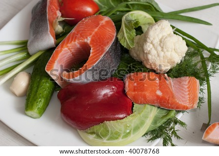 Stake of a trout on a white plate with vegetables