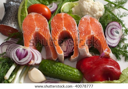 Three stakes of a trout on a plate with vegetables