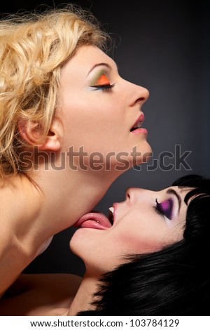 stock photo : Two young attractive lesbians kissing isolated on gray background