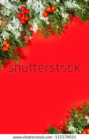 Christmas green  framework, postcard with snow, cones and holly berry  isolated on red paper background