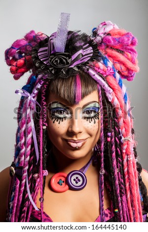Portrait of a stylish young woman with multicolored dreadlocks and with stylish make-up in doll style. Creative make-up.Fantasy dress.