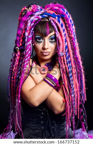 Portrait of a stylish young woman with multicolored dreadlocks and with stylish make-up in doll style. Creative make-up.Fantasy dress.