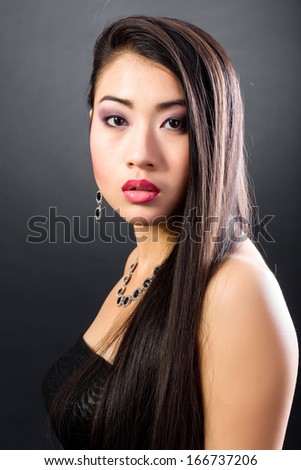 Beauty Portrait. Beautiful brunette Asian woman with long black hair. Shot in a studio on a black background