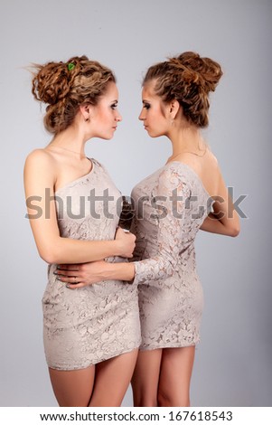 Two beautiful girls twins, isolated on the grey background - stock photo