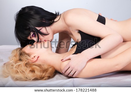 Two young attractive lesbians kissing isolated on gray background