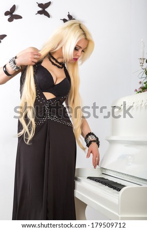 beautiful young attractive woman in evening dress and piano in a light room