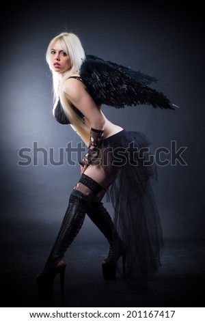 Woman in the lingerie with black angel wings against the black background