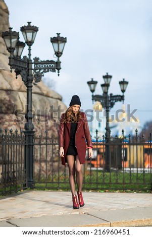 Portrait of a young woman in a city park, next to  iron street lamp