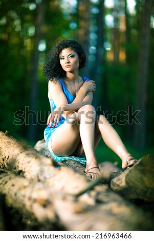 Beautiful Young Woman sitting on log posing on a warm summer day