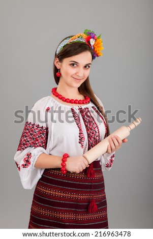 Housewife with rolling pin. Woman wears Ukrainian national dress isolated on grey background