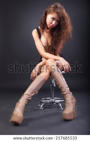 Beautiful young woman wearing boots. Image isolated against black background.