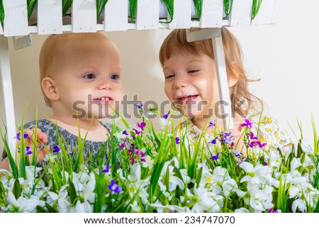 Cute little child girls with spring flowers, happy baby girl with basket of flowers.