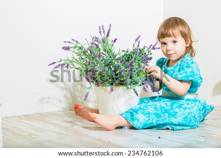 Cute little child girl with spring flowers, happy baby girl with basket of flowers.