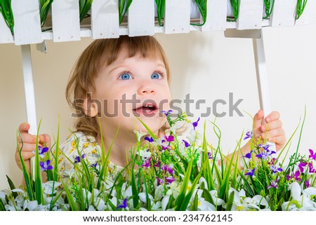 Cute little child girl with spring flowers, happy baby girl with basket of flowers.