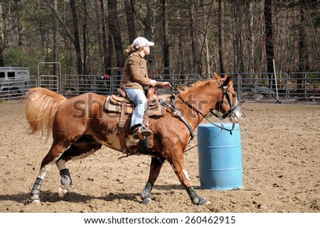 Young blond woman training her horse for barrel racing