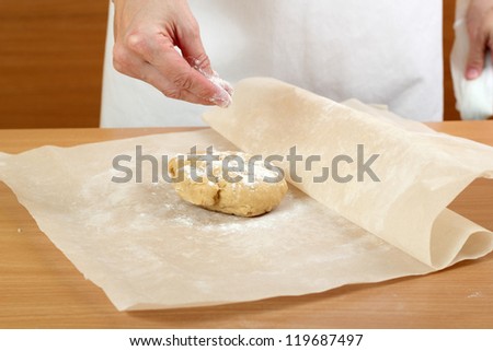 Making Pastry Dough for Hungarian Cake. Series. A baker rolling a dough between sheets of baking paper.