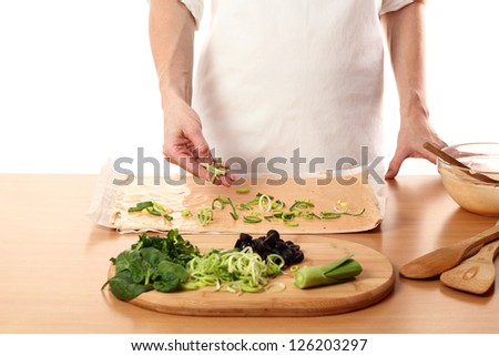 Making Pizza with Leek and Spinach. Series. Spreading sliced leek on dough.