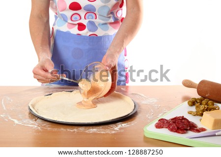 Making Pizza with Salami, Olives and Cheese. Series. Pouring Tomato Sauce into Dough Sheet.