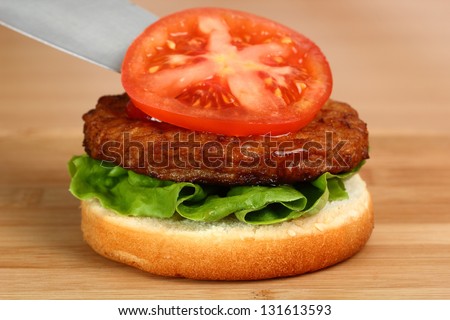 Making Hamburger. Macro. Series. 8/12. Put Tomato on Patty.