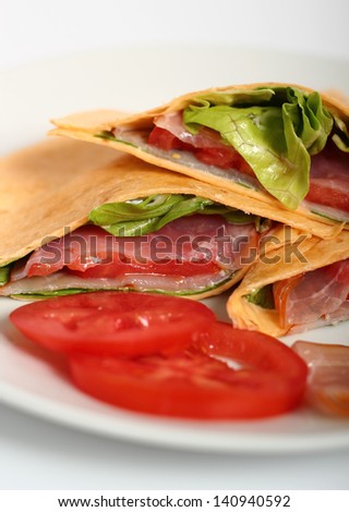 Wrap tortilla sandwich with ham, tomato, lettuce. Isolated with clipping path.