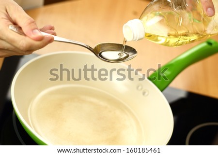 Pouring vegetable oil into frying pan. Making enchilada tortilla with beef.