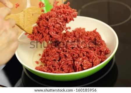 Adding ground beef into frying pan. Making enchilada tortilla with beef.