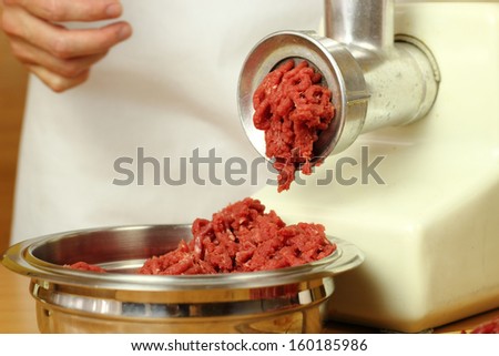 Mincing beef by meat grinder. Making enchilada tortilla with beef.