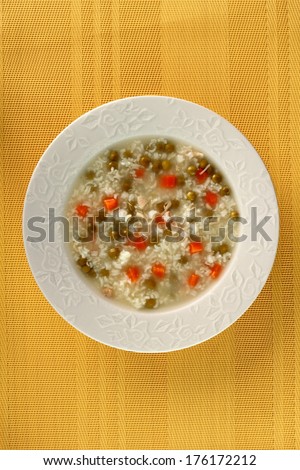 Rice soup with chicken, green peas and carrots. Directly Above.
