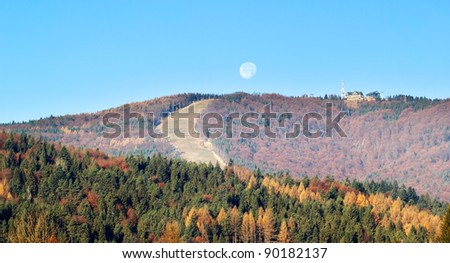 Full moon setting at sunrise over autumn mountains in Beskids