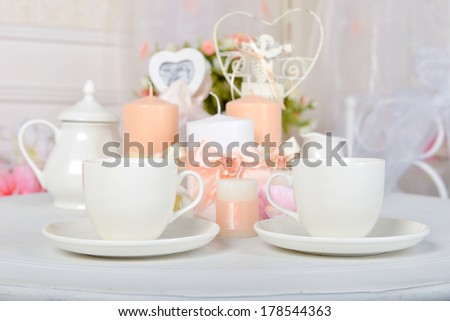 Coffee cups and candles on a white table. Romantic dinner.