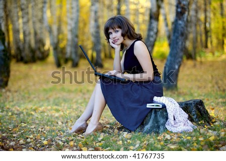 Young businesswoman using laptop in the birch forest.