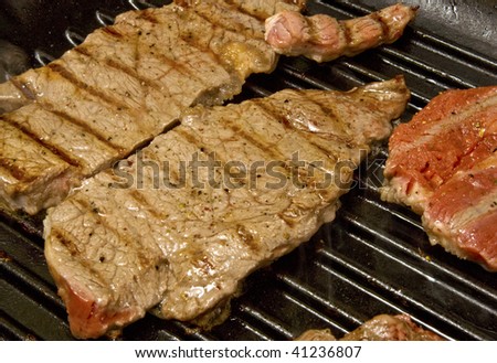 Steak cooking in griddle pan with smoke