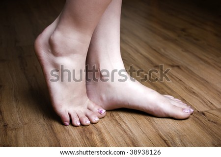 stock photo Woman's beautiful feet with nail art on a wooden floor