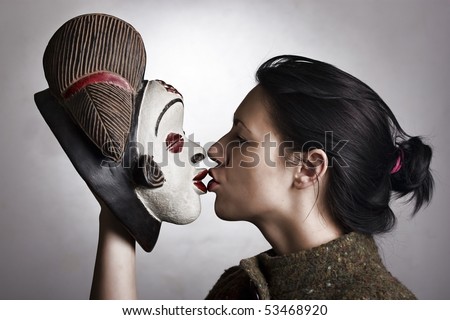 Portrait of a woman holding a traditional African mask and kissing it.