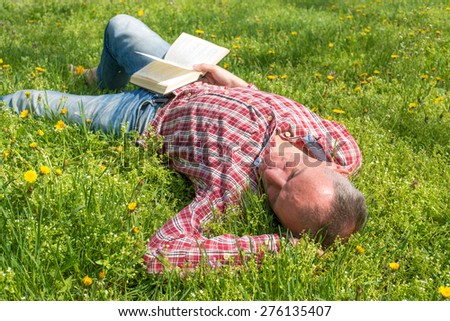 Man sleeps on a meadow with a book in hand