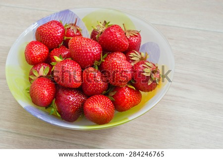 Homemade food. Plate with fresh strawberries on a wooden background