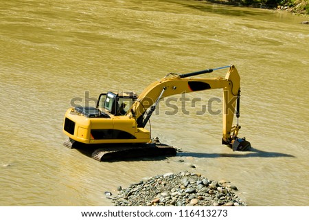 excavator machine during earthmoving in a river, logos removed